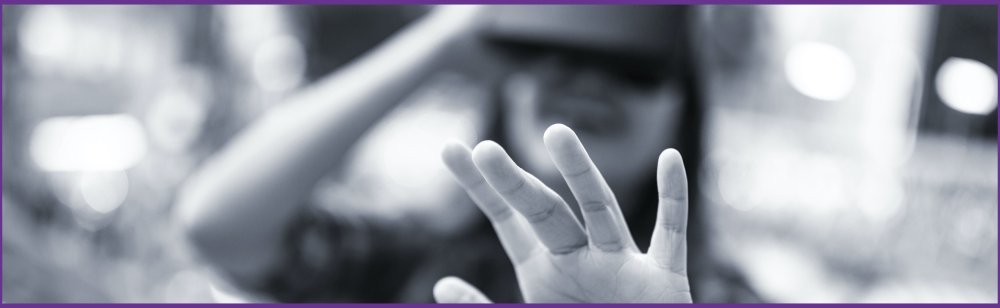 A woman wearing a virtual reality (VR) headset, laughing, reaching out in front of her